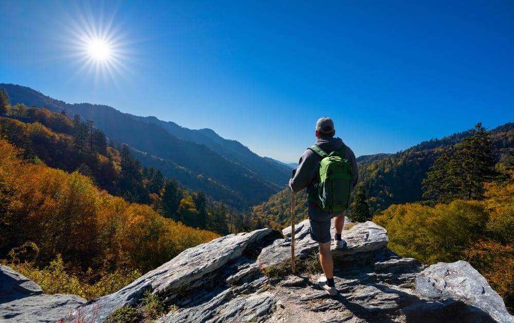 A hiker admiring the sun on a rocky mountain in a national park.