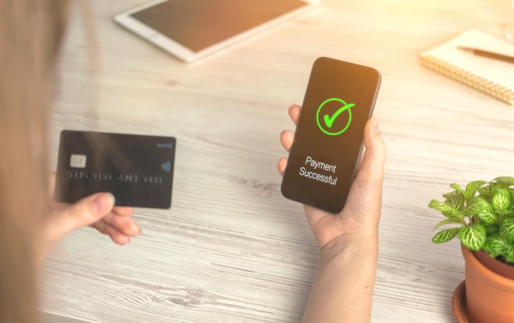 A woman is using a mobile app to make credit card payments, conveniently avoiding any additional fees.