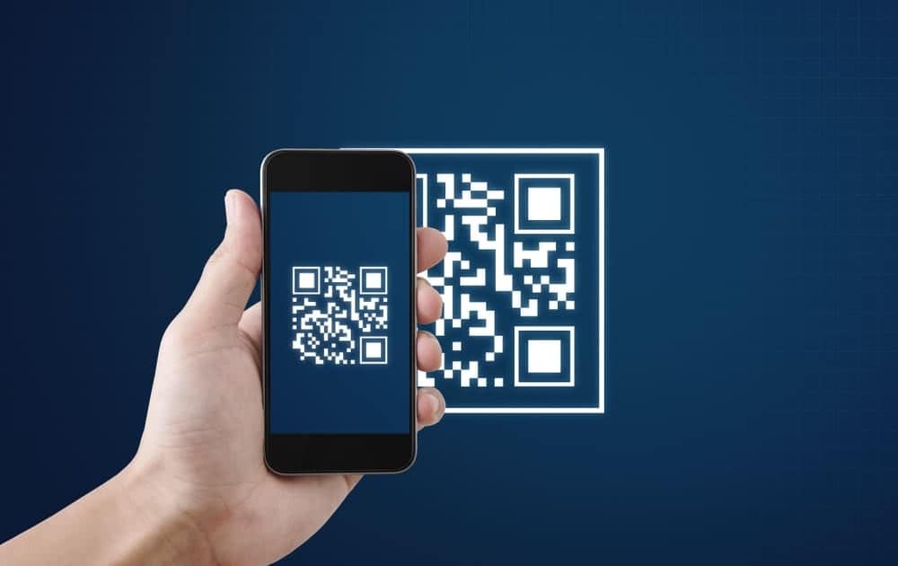 A hand holding a smartphone displaying a qr code for scan and pay.