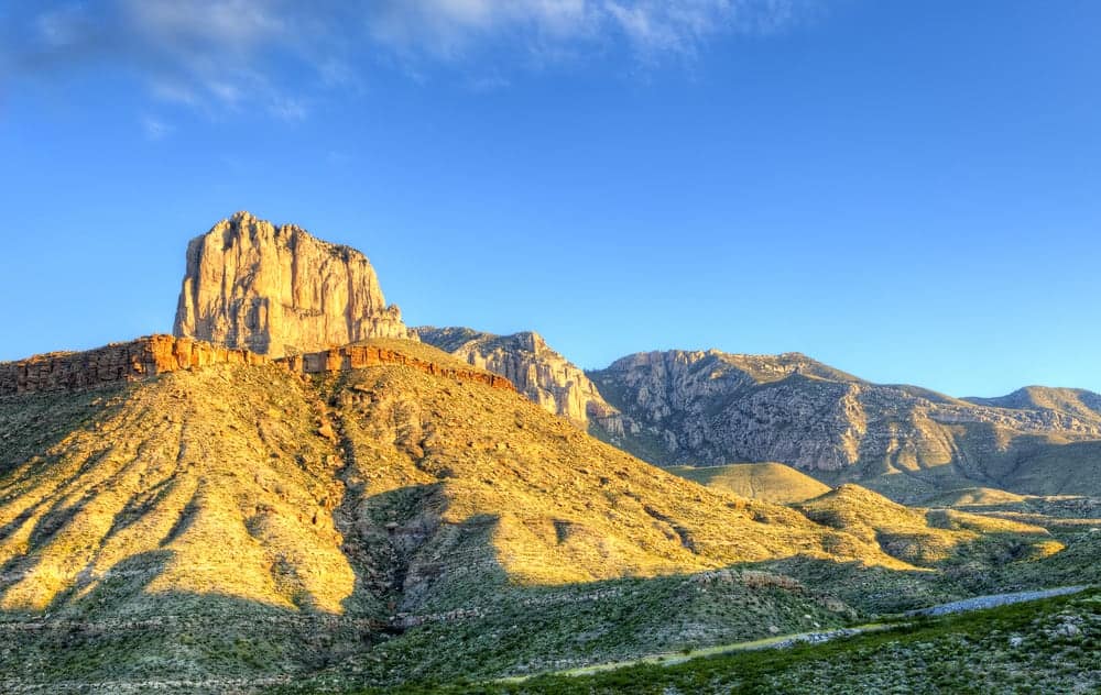 A mountain range with a large rock formation in the background located in Guadalupe Mountains National Park.