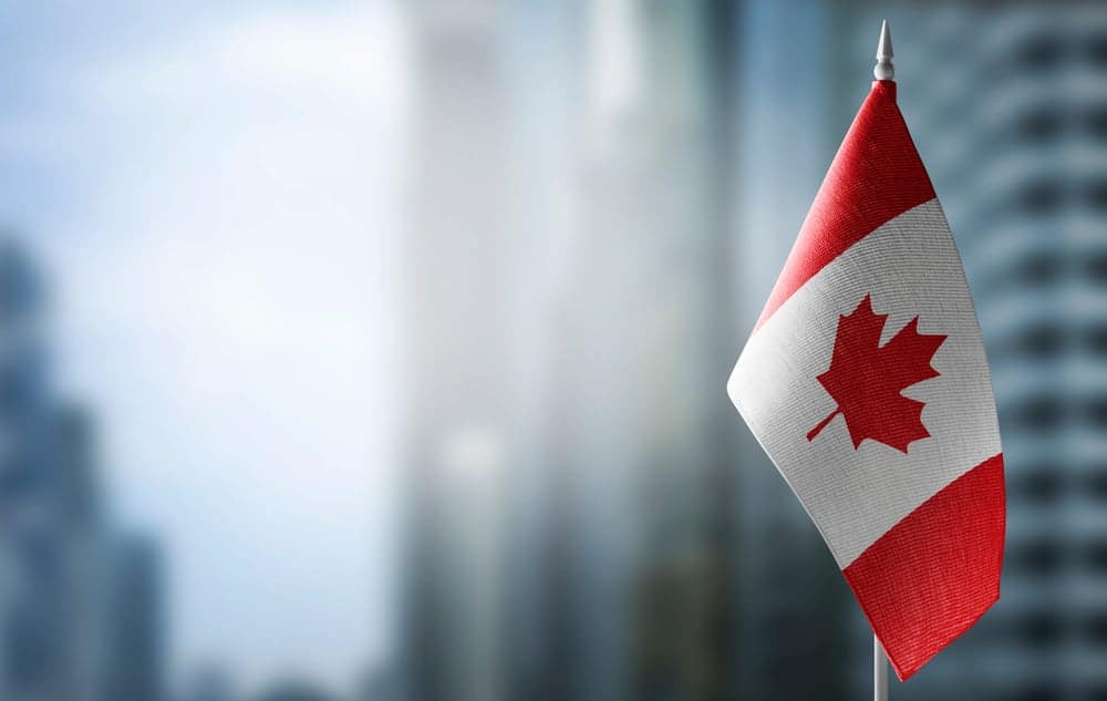 A Canadian flag is flying in front of a city, representing the pride and patriotism of the Canadian Gov't.