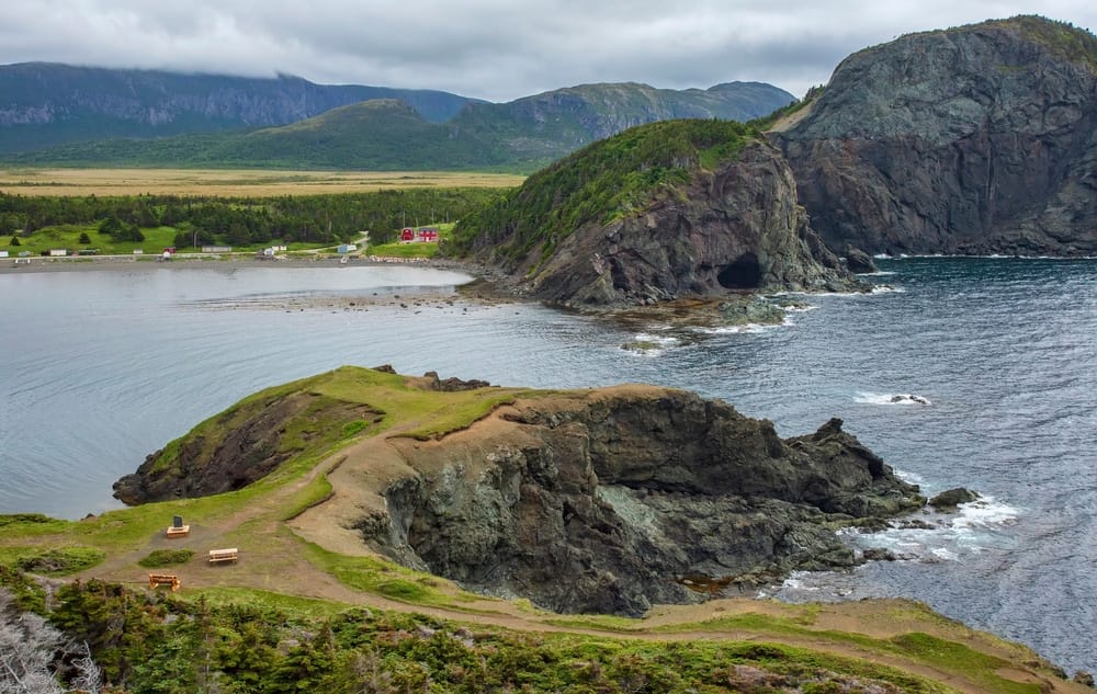 A rocky cliff overlooking the ocean and a small village near Bottle Cove.