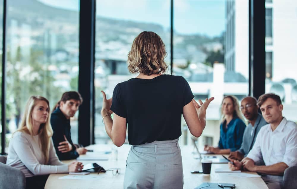 A woman giving a presentation to a group of people in a conference room at Snow Peak USA.