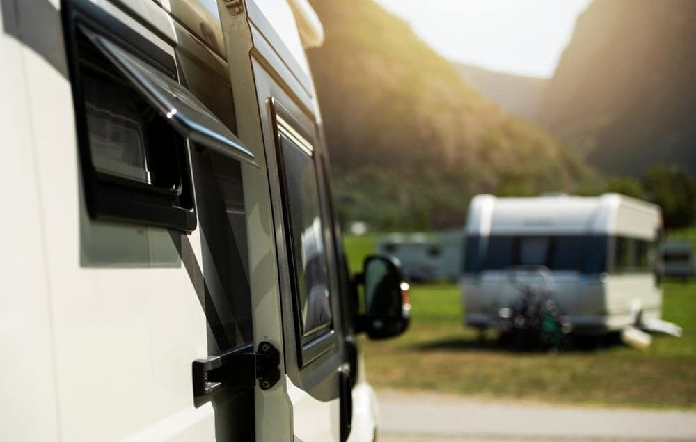 An rv parked in a field with mountains in the background at an Alberta campground.
