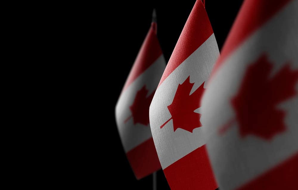 Three canadian flags in the wind on a black background, symbolizing national unity and solidarity.