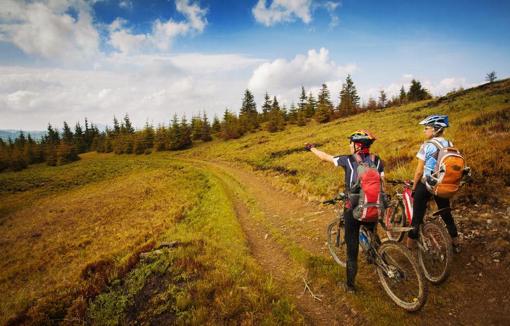 Two mountain bikers on a trail in April 2022, enjoying their outdoor recreation while surrounded by the breathtaking mountains.