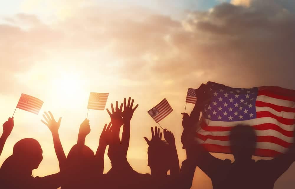 Silhouettes of people waving american flags at a 4th of July celebration in La Crosse.