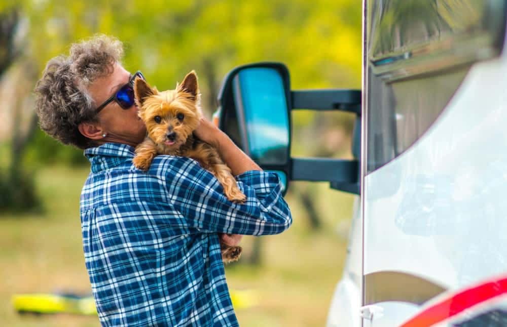 A man holding a dog in front of a Lazydays RV, participating in the Instagram Contest for National Pet Day.