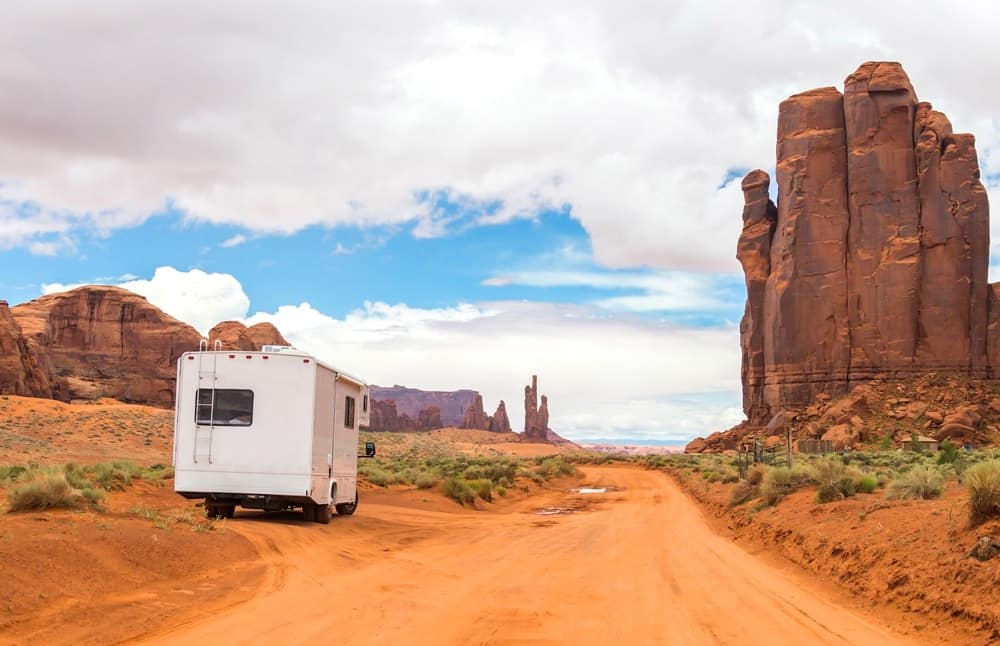 An rv is parked on a dirt road in monument valley during camping season.