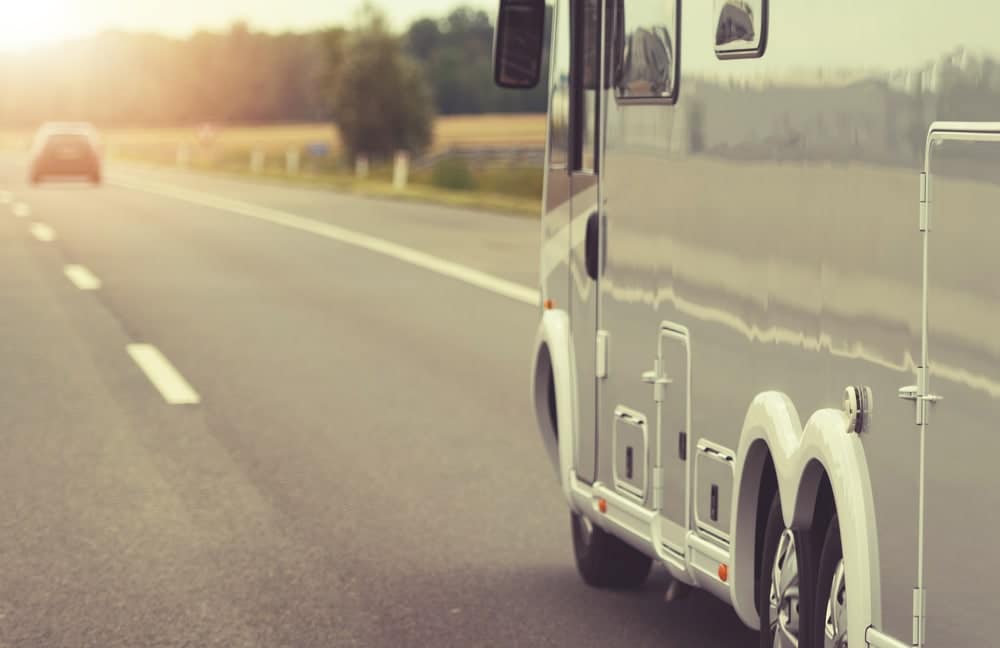 A white rv is driving down the road.