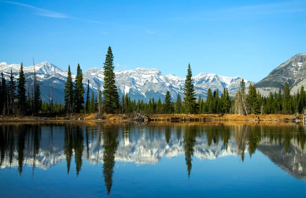 Bow Valley Tourism initiates sustainable growth in the region as a mountain range is reflected in a serene lake.
