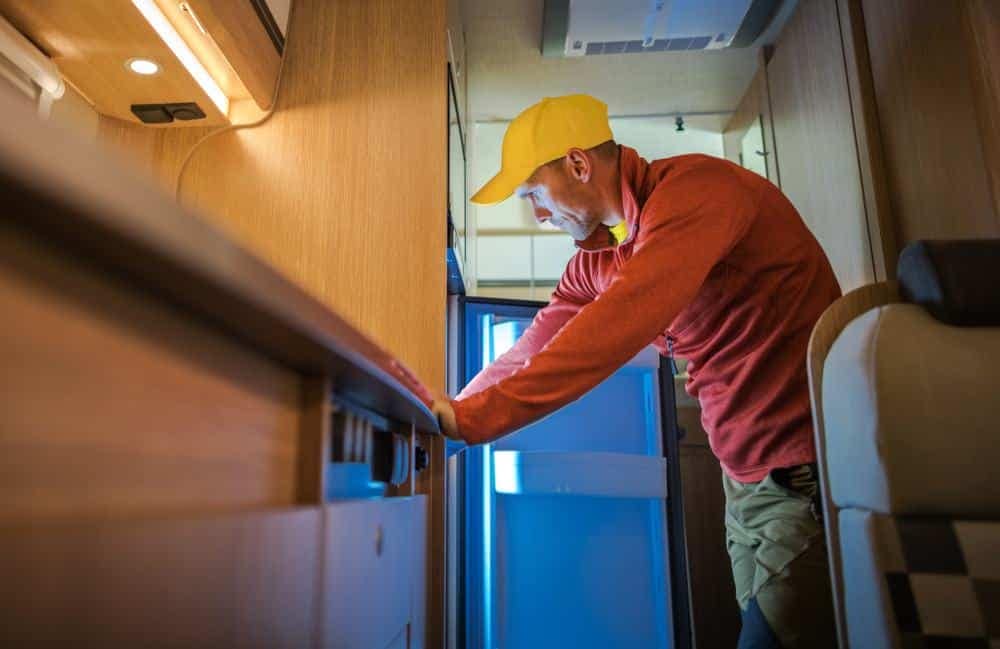 A man in a yellow hat is opening the door of a Dual Swing RV.