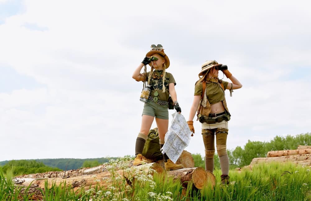 Two women in military uniforms standing on top of logs at the Get Out There Event.