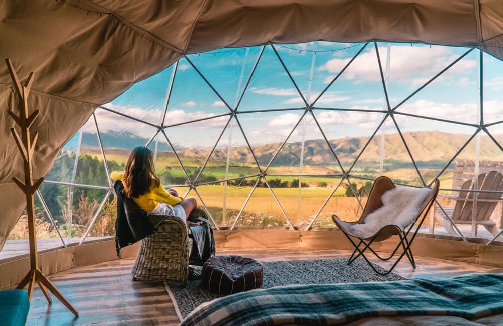 A woman is sitting in an igloo with a view of the mountains.