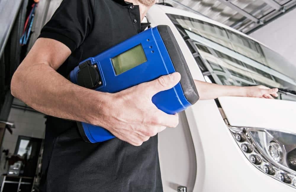 A man holding a blue tablet in front of a truck during Certification Week.