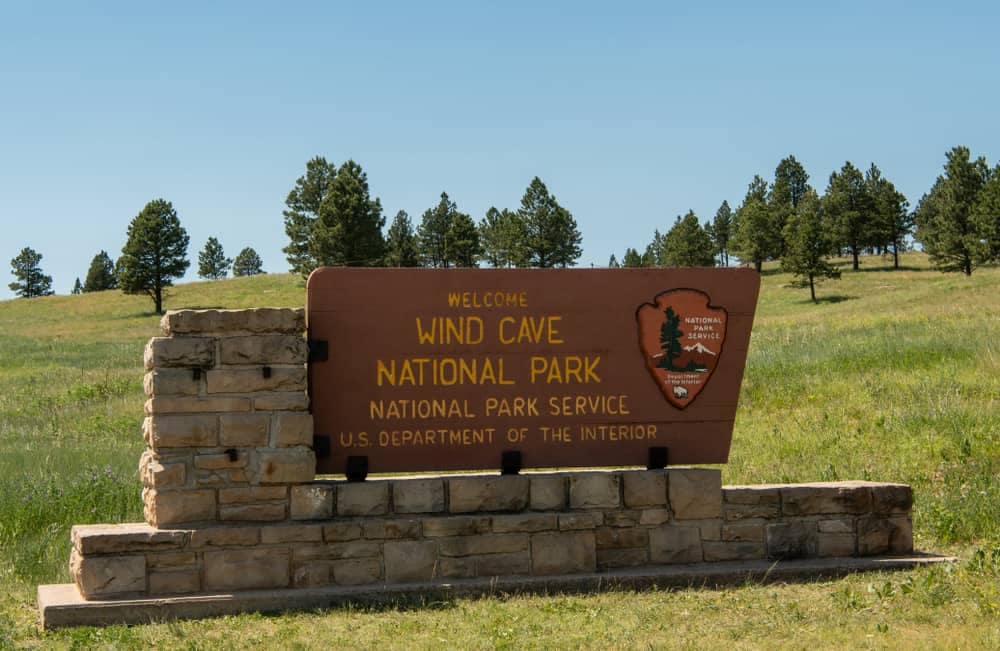 A sign for Wild Oats National Park in the middle of a grassy field, showcasing the beautiful landscape and inviting visitors to explore.