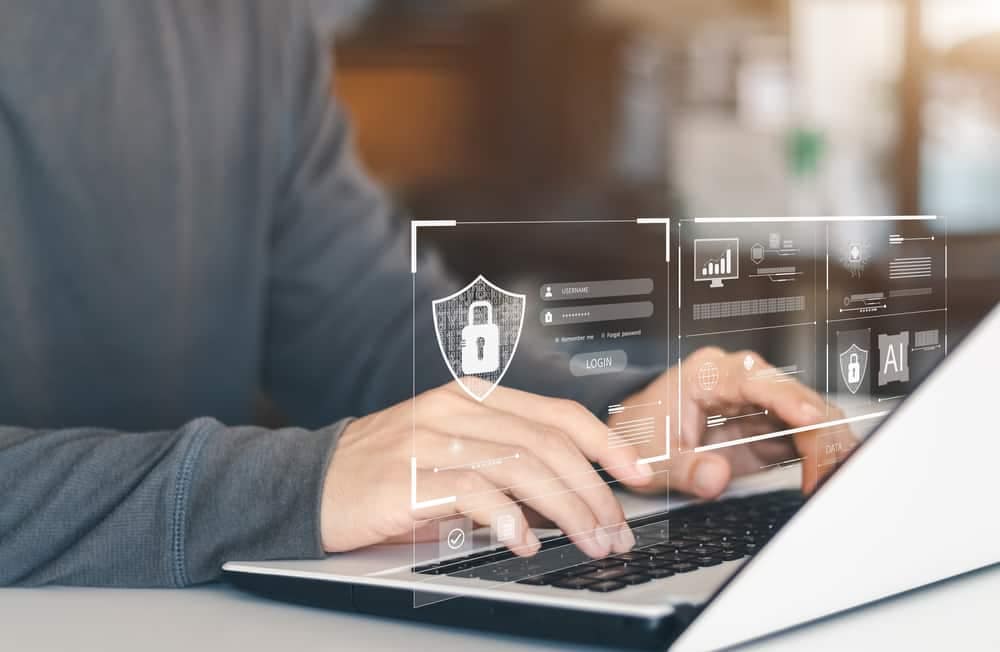 A man participating in a cybersecurity workshop, typing on a laptop with a security symbol on it.