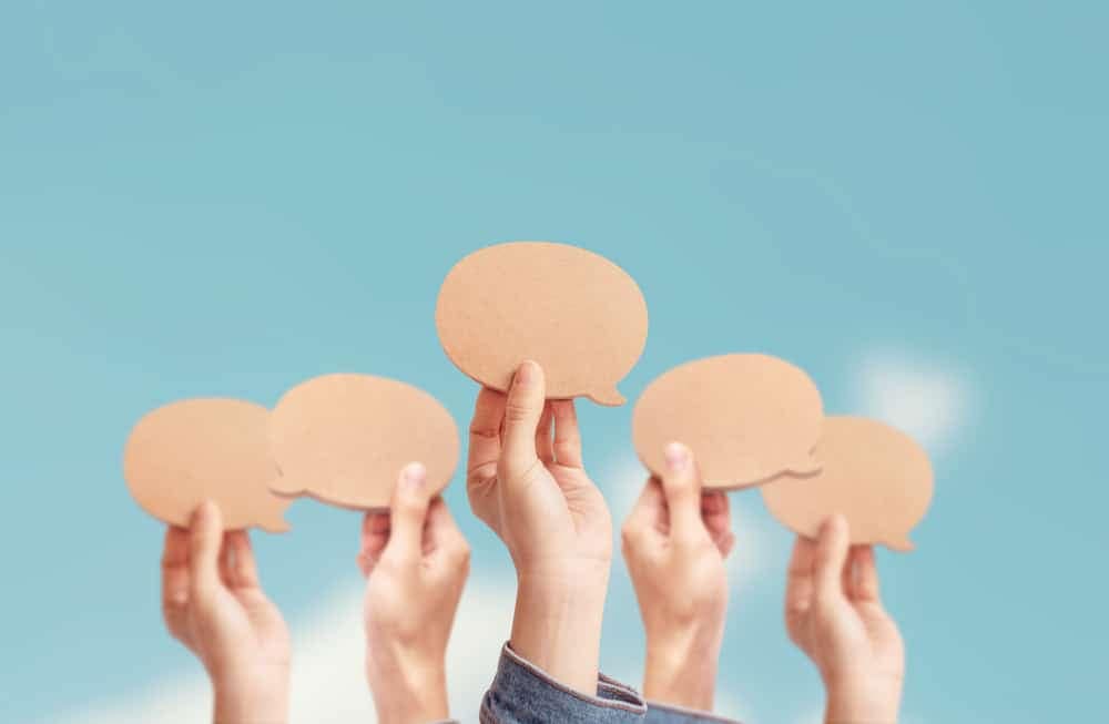 A group of hands holding paper speech bubbles discussing Land Management.