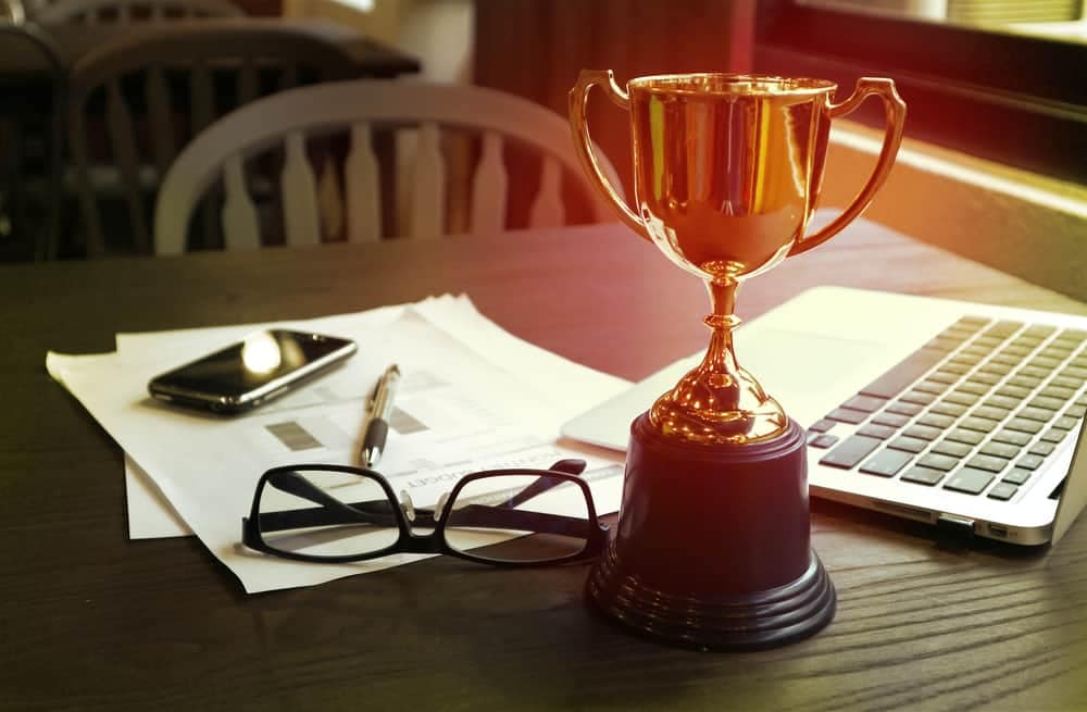An impressive trophy sits on a desk next to a laptop, symbolizing the gamechanger achieved by the franchise CMO.
