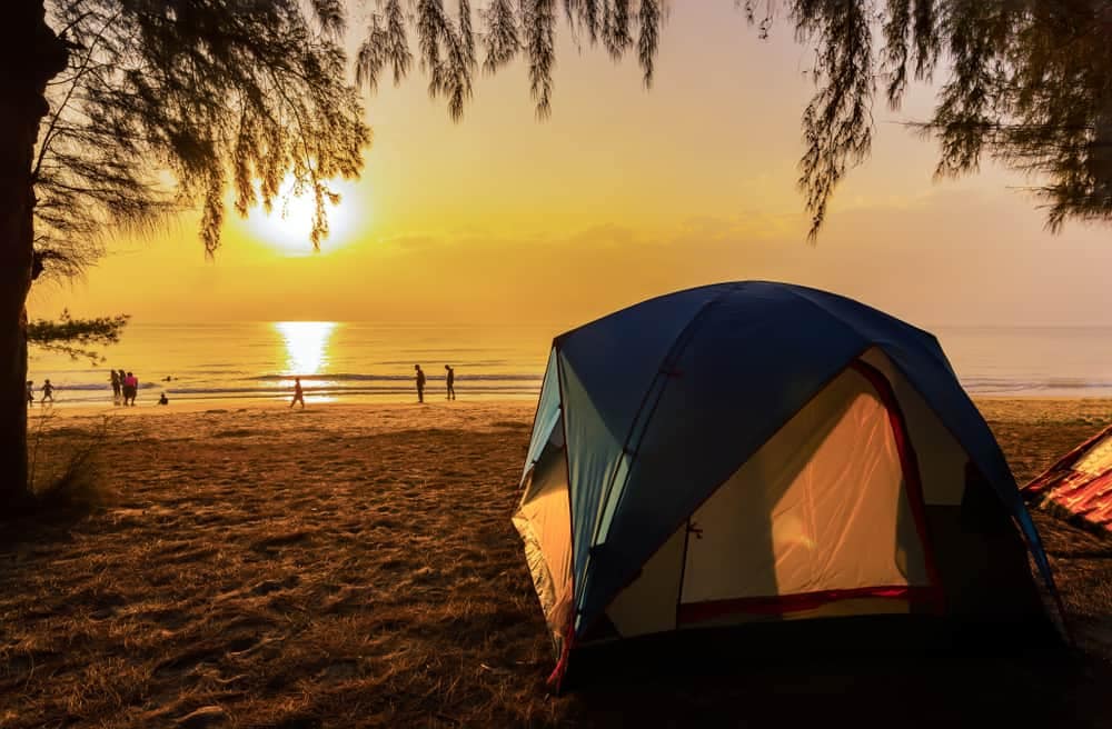A camping tent set up on the beach at sunset.