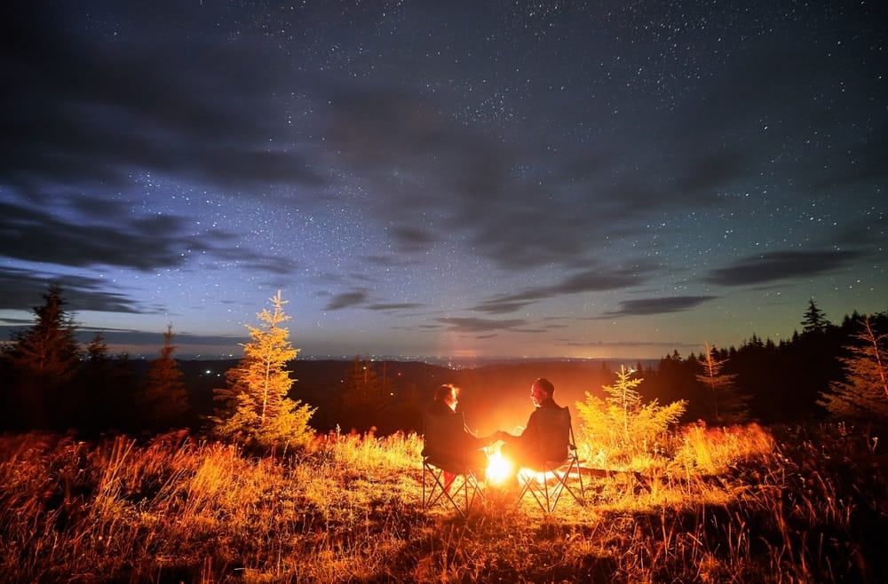 Two people enjoying a cozy campfire on a crisp fall night during the Labor Day weekend.