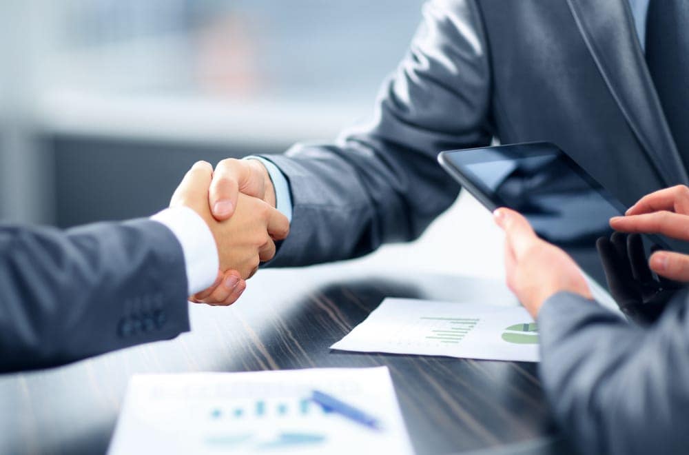 Two business people shaking hands over a table at RMS North America.