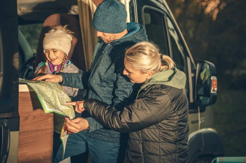 A family using a map in the back of an RVshare camper van to enhance their camping awareness.