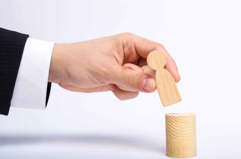 Minister Josie Osborne is demonstrating resource stewardship by placing a wooden figure into a cylinder.