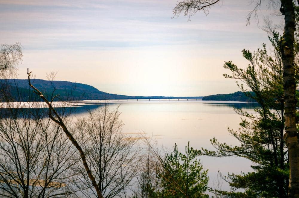 A picturesque view of Great Sacandaga Lake with lush trees and a charming bridge.