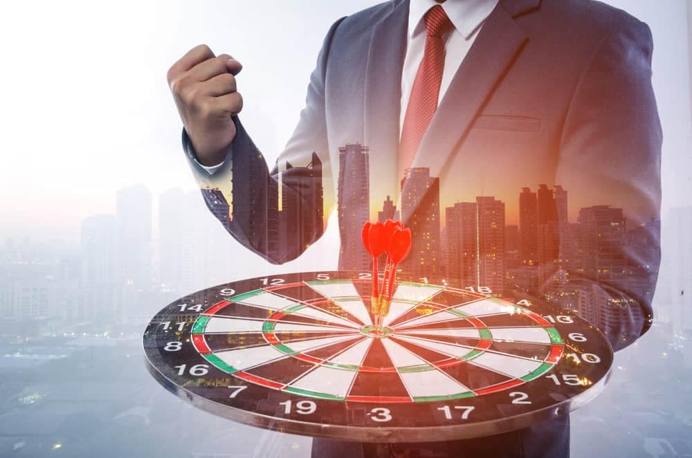 A businessman is holding a dart in front of an Annual Risk Reduction Target.