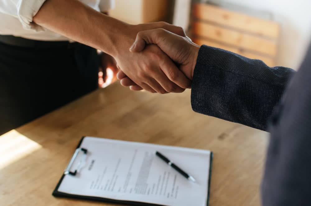 Two business people shaking hands over a document in Nahanni National Park Reserve.