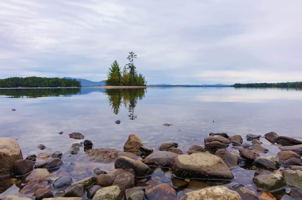 A lake with rocks in the middle, located within Maine State Park.