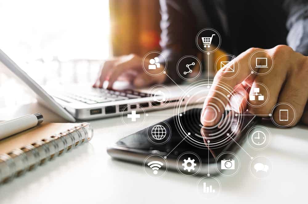 A man is using a laptop and a smartphone to access online resources.