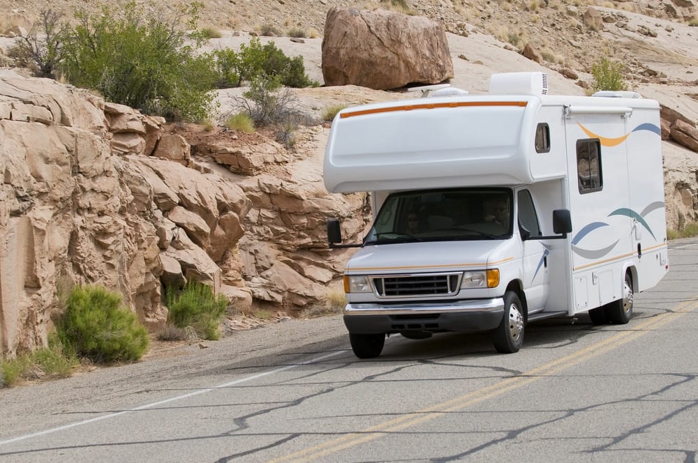 A white rv driving down the road.