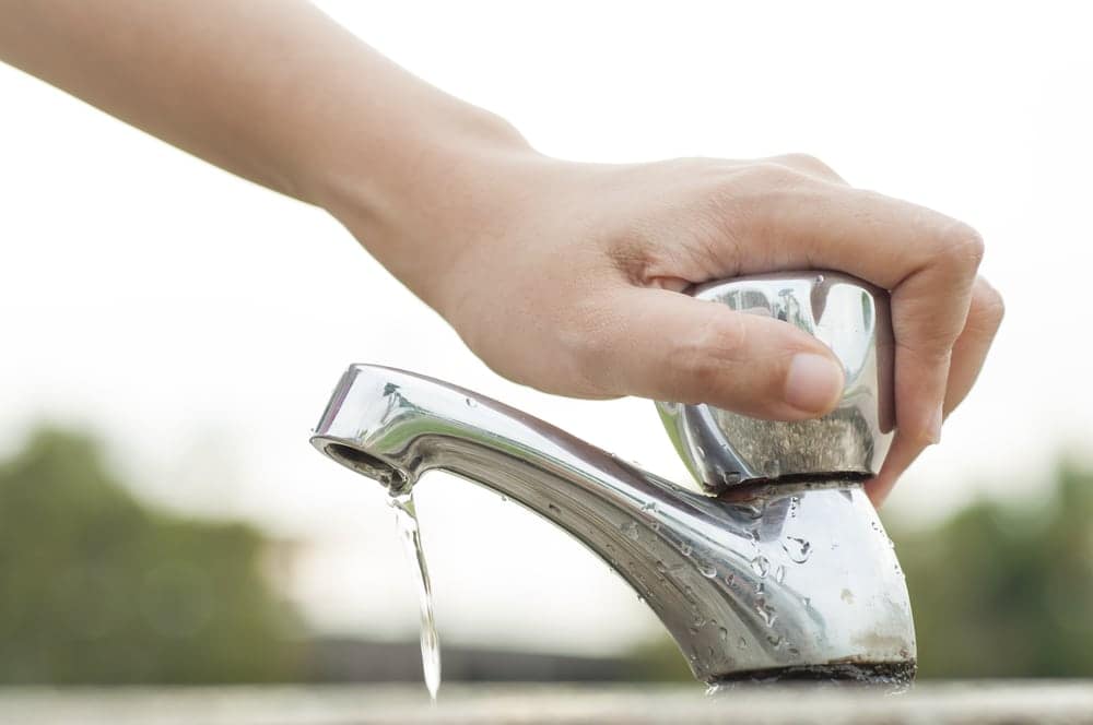 A person is pouring water from a faucet at an Encore RV Resorts, demonstrating water conservation and sustainability efforts.