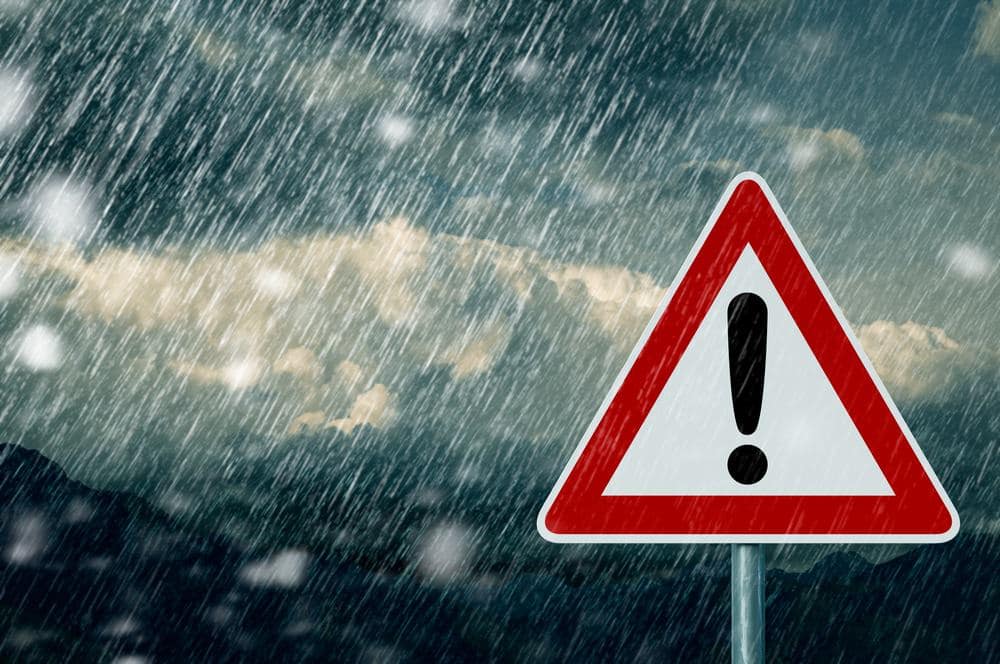 A warning sign in the rain with a mountain in the background.
