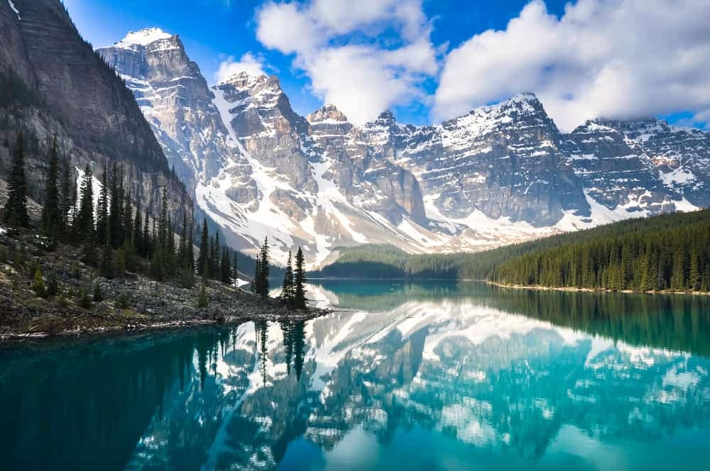 The mountains are reflected in the water of a lake in Banff National Park, a stunning location managed by Parks Canada.