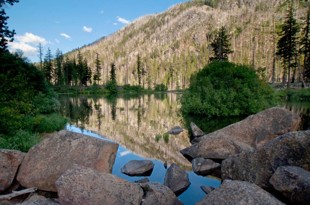 Celebrate National Get Outdoors Day with free access to a picturesque lake, nestled among rocks and trees.