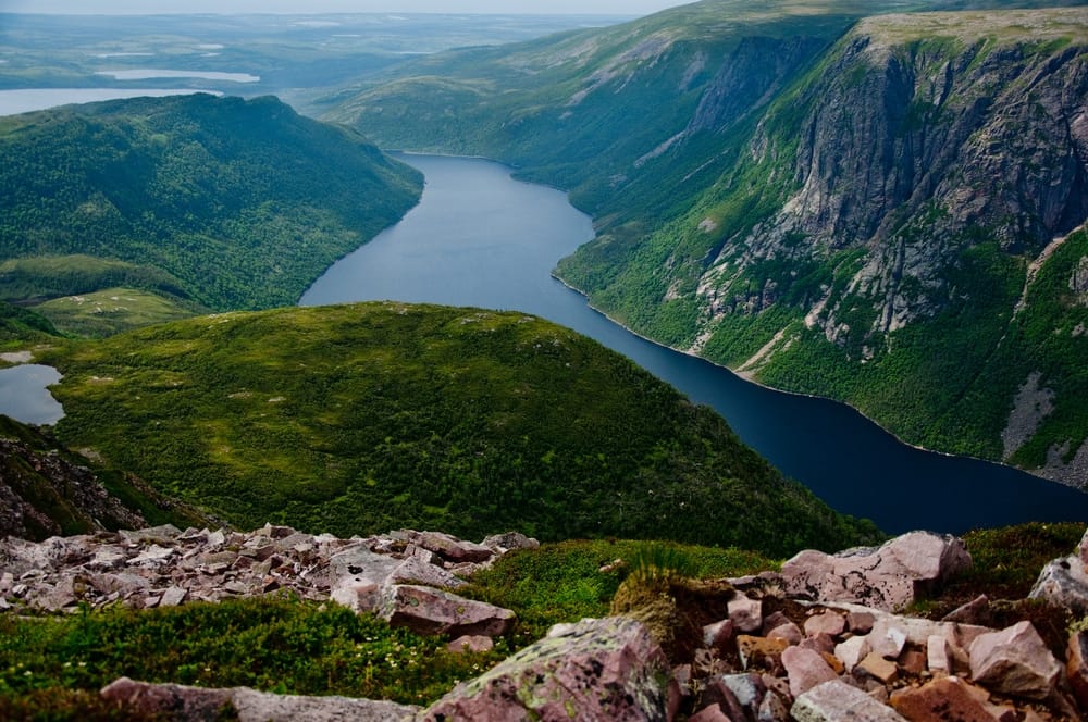 A view from the top of a mountain overlooking a lake, showcasing Newfoundland and Labrador's Tourism Industry.