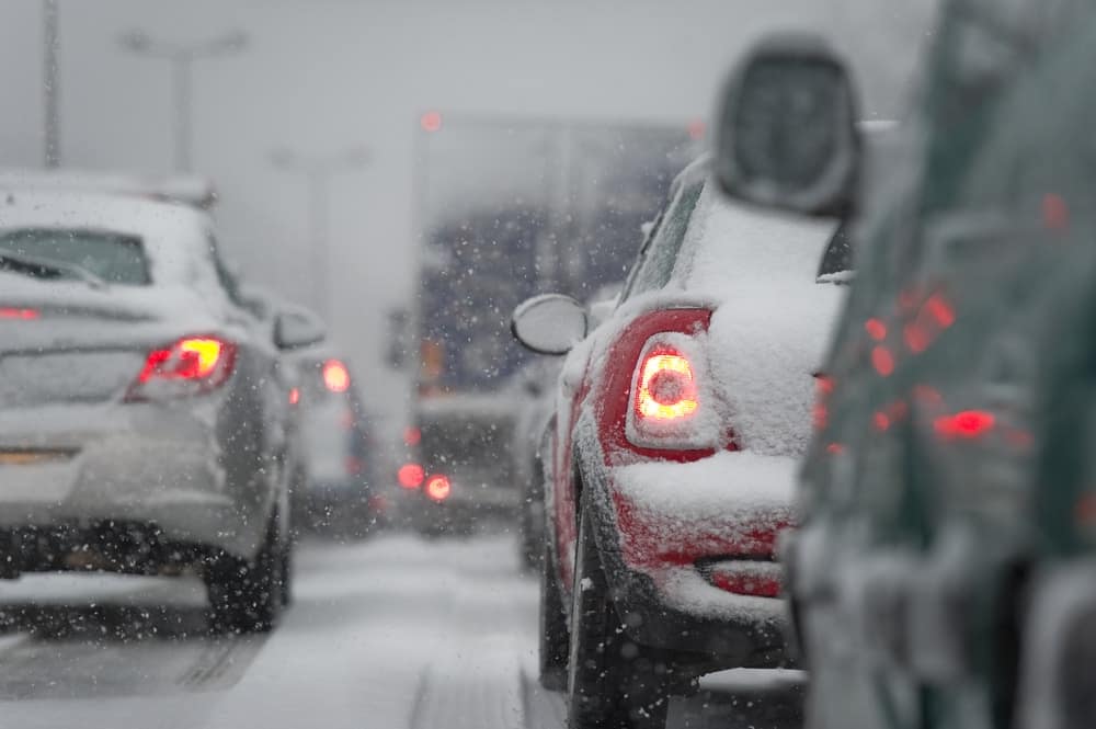 A traffic jam on a snowy road in New York, with cars covered in snow.