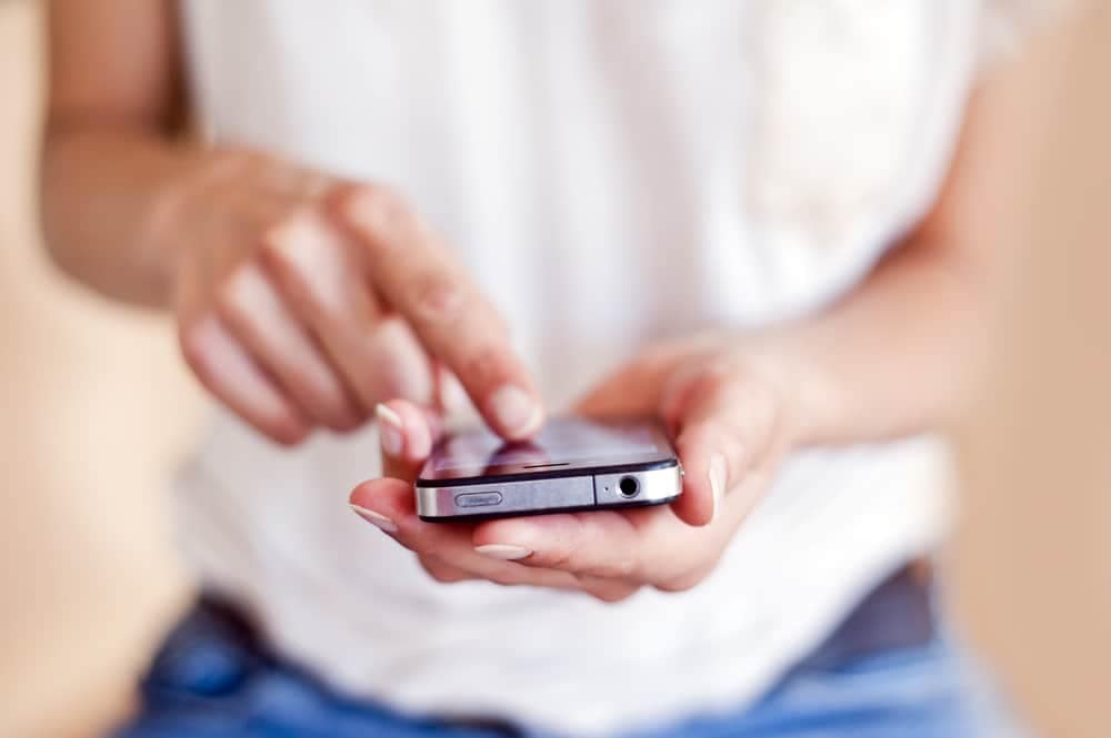 A woman is holding a cell phone in her hand while checking her E-Trailer's E-Gaslevel.