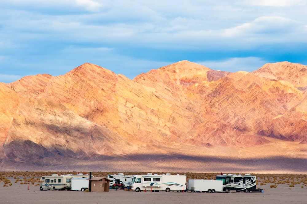 A group of travelers' RVs parked in a magnificent desert landscape, with stunning mountains in the background.