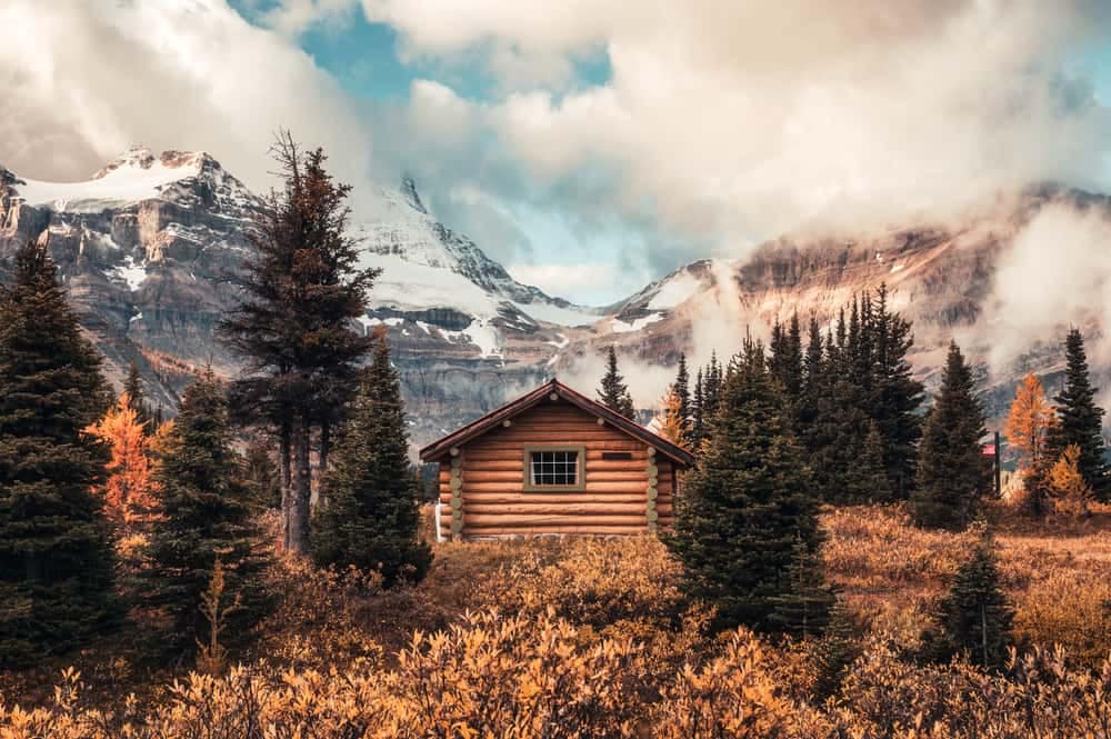 A cabin sits in the middle of a forest with mountains in the background while the Victorian Labor Government contributes AU$5 million for Caravan Parks Upgrades.