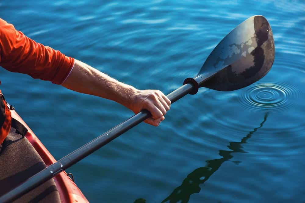 A man from Stz'uminus First Nation is paddling a kayak with a paddle.