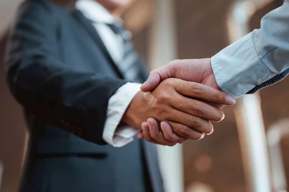Two businessmen shaking hands in front of a building, signifying the new members joining the RV Industry Association.