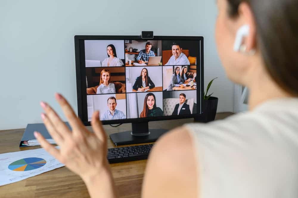 A woman participating in a Roundtable discussion on Outdoor Recreation, with a computer screen displaying several people on a video conference.