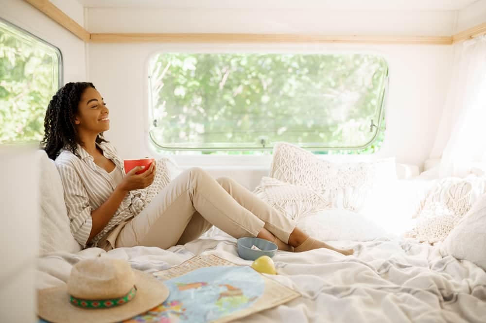 A woman resting in bed with a cup of coffee, enjoying the comfort of her Brooklyn Bedding mattress.