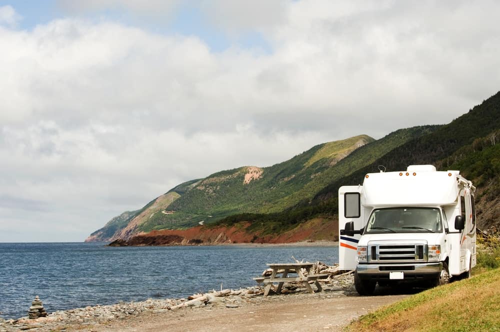 A white RV parked on the side of the road near the ocean in Nova Scotia.