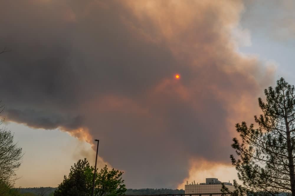A large plume of smoke rises from the ground in Canada, signifying wildfires and impacting outdoor tourism.