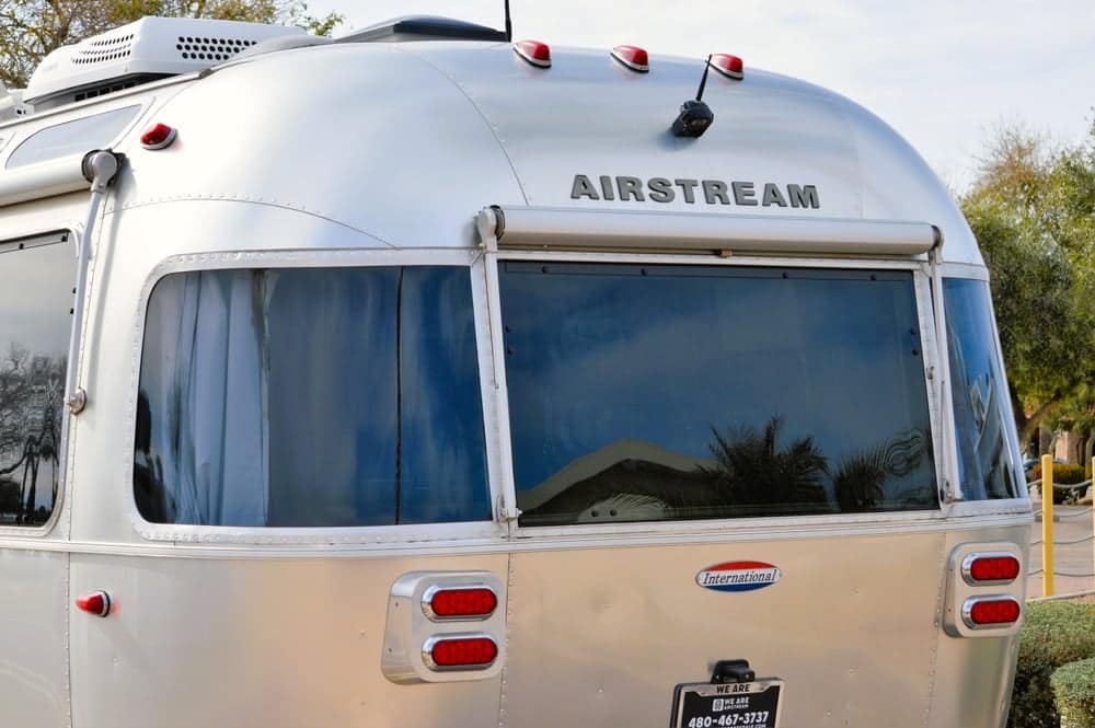 A silver Airstream, representing the Airstream Club at the International Rally, is elegantly parked in a parking lot.